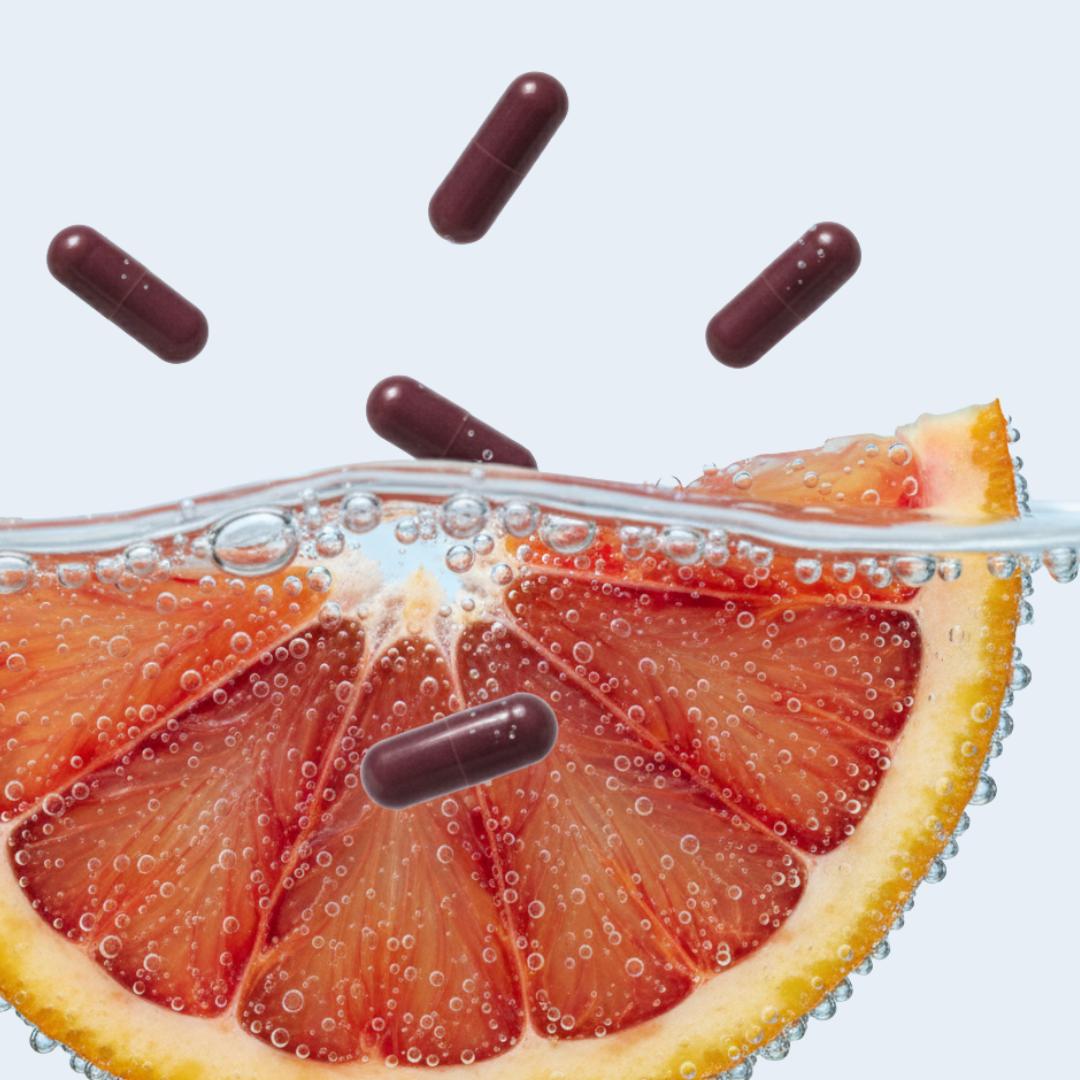 Gélules de morosil au-dessus d’une tranche d’orange sanguine dans l’eau